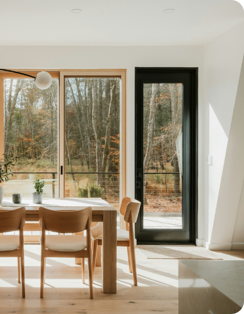 Warm oak dining table and black steel-framed windows.
